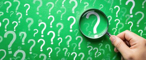 The magnifying glass highlighting questions on a green background. photo