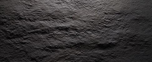 The textured black stone surface with intricate details and shadows. photo
