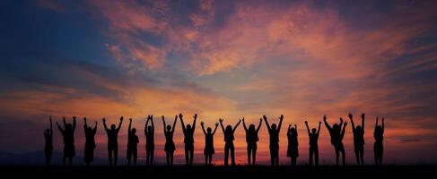 The silhouettes of a joyful group celebrating under a vibrant sunset sky. photo