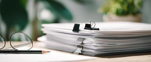 The stack of organized documents and stationery on a wooden workspace. photo