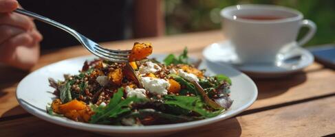 The vibrant salad with quinoa and pumpkin served alongside a cup of tea. photo