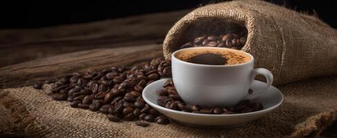 The coffee cup surrounded by fresh roasted beans on rustic burlap. photo