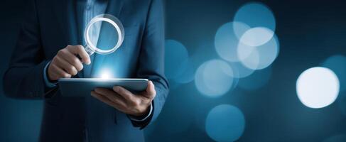 The professional analyzing data on a tablet with a magnifying glass effect. photo