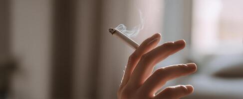 The hand holding a cigarette releasing soft smoke in a cozy atmosphere photo