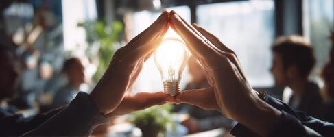 The hands protecting a glowing lightbulb as a symbol of innovative ideas. photo