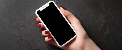 The mobile smartphone held elegantly in a stylish hand against a dark background. photo