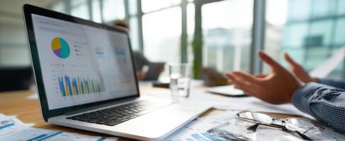 The laptop displaying graphs and data in a collaborative business environment. photo
