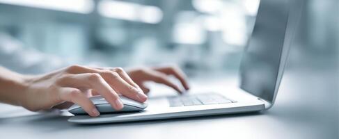 The hands of a professional using a laptop and mouse in a modern workspace. photo