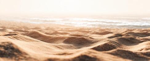 The sandy beach with gentle waves under a warm sunlit horizon. photo