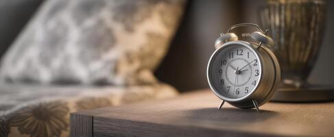 A clock on a table in front of a bed photo