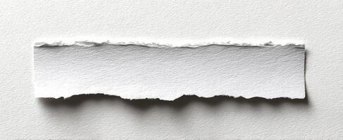 The torn white paper strip against a clean background for creative design use. photo