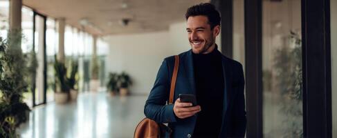 The smiling businessman with phone and leather bag in a modern corridor. photo