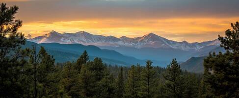 The breathtaking mountains at sunset with a tranquil forest foreground. photo