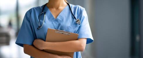 The healthcare professional in scrubs holding a clipboard in a hospital setting. photo