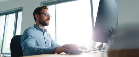 The focused man working diligently at a computer in a modern office space photo