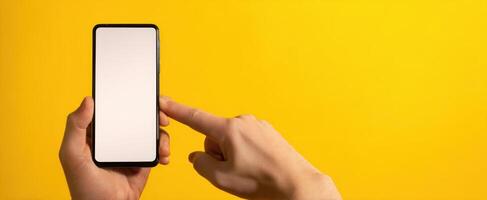 The hand pointing at a smartphone screen against a vibrant yellow background. photo