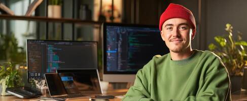 The young programmer smiling in a modern workspace with dual monitors. photo