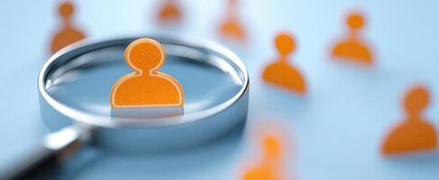 The magnifying glass highlighting a distinctive orange figure among several people icons. photo