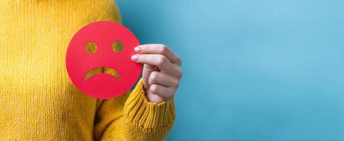 The emotion of sadness expressed through a hand-held red paper sad face photo