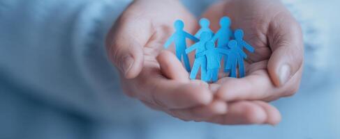 The hands holding blue paper figures representing family and community support. photo