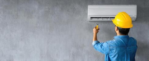 The technician installing an air conditioning unit on a concrete wall. photo