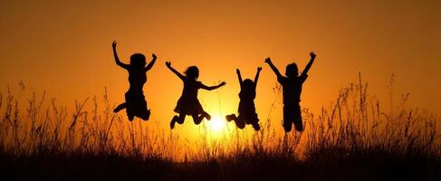 The joyful children jumping against a beautiful sunset silhouette. photo