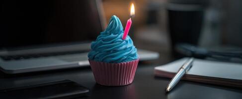 The colorful cupcake with a candle set on a stylish office desk. photo