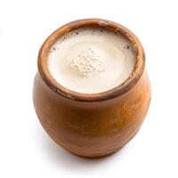 A brown clay pot with milk and a spoon photo