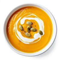 A bowl of butternut squash soup with roasted pumpkin seeds and a swirl of cream, isolated on clean photo