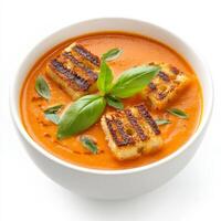 Tomato basil soup with grilled tofu cubes in a bowl isolated on white background photo