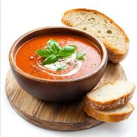 A rustic wooden table set with a bowl of steaming tomato soup, topped with a swirl of cream and photo