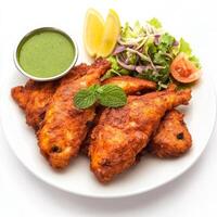 A plate of fish amritsari, with fish marinated in spices and gram flour, fried until crispy, served photo
