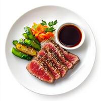 A beautifully arranged image of a plate of seared tuna steak, served with a side of sesame-ginger sauce and pickled vegetables. The seared tuna steak, with its tender, rare center and flavorful sesame photo