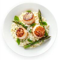 An artistic arrangement of a plate of seared scallops, served on a bed of creamy risotto with asparagus and Parmesan cheese. The seared scallops, with their delicate sweetness and buttery texture, photo