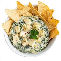 A bowl of spinach and artichoke dip, with a creamy blend of spinach, artichokes, cream cheese, parmesan cheese, garlic, and herbs, served with tortilla chips, vegetable sticks, toasted baguette slices photo
