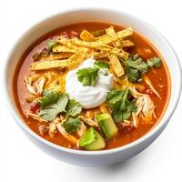 A close-up of a bowl of spicy chicken tortilla soup, with a rich tomato broth, shredded chicken, crispy tortilla strips, avocado, cheese, and sour cream. isolated on clean white background. photo