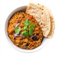 A bowl of baingan bharta, with roasted eggplant mashed and cooked with tomatoes, onions, and spices, served with roti, isolated on clean white background. photo