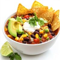A bowl of vegetable and black bean chili, with tender vegetables, black beans, corn, spices, and a touch of cocoa, simmered in a flavorful tomato-based broth, served with avocado, sour cream, tortilla photo