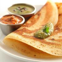 A close-up of a rava dosa, with a crispy crepe made from semolina batter, served with coconut chutney and sambar, isolated on clean white background. photo