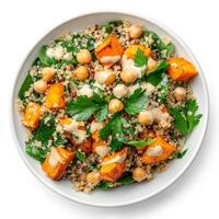 A colorful quinoa salad with roasted sweet potatoes, chickpeas, spinach, and a lemon-tahini dressing, garnished with fresh parsley, isolated on clean white background. photo
