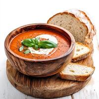 A rustic wooden table set with a bowl of steaming tomato soup, topped with a swirl of cream and fresh basil leaves. The soup, a vibrant red, emits a comforting aroma of ripe tomatoes and herbs. Next photo