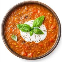 A bowl of creamy tomato and lentil soup, with tender lentils, tomatoes, carrots, celery, onions, and garlic, blended until smooth and creamy, topped with a swirl of coconut cream and fresh basil photo