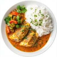 A plate of goan fish curry, with fish cooked in a tangy coconut and kokum sauce, served with rice and a side of vegetable xacuti, garnished with cilantro, isolated on clean white background. photo