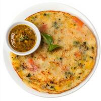 A close-up of a uttapam, with a thick pancake made from rice and lentil batter, topped with vegetables, served with sambar and chutney, isolated on clean white background. photo