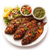 A plate of fish amritsari, with fish marinated in spices and gram flour, fried until crispy, served with mint chutney and a side of salad, garnished with lemon wedges, isolated on clean white photo