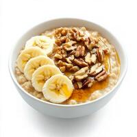 A bowl of warm oatmeal topped with sliced bananas, crushed walnuts, and a drizzle of maple syrup. A comforting and nutritious breakfast option. Isolated on clean white background photo