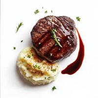 A perfectly seared filet mignon, cooked to a tender medium-rare, with a side of creamy mashed potatoes and a drizzle of red wine reduction sauce. A gourmet steakhouse dish. Isolated on clean white photo