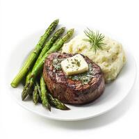 A plate of perfectly cooked filet mignon, topped with a pat of herb butter, served with garlic mashed potatoes and grilled asparagus. A fine dining experience. Isolated on clean white background photo