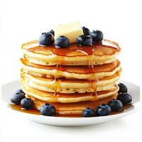 A stack of fluffy pancakes drizzled with golden maple syrup, topped with a pat of melting butter and a handful of fresh blueberries. The layers are perfectly even, making for an irresistible breakfast photo