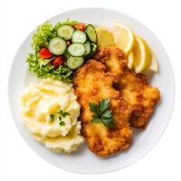 A plate of golden-brown chicken schnitzel, served with a side of buttery mashed potatoes, lemon wedges, and a fresh cucumber salad. A classic European dish. Isolated on clean white background photo